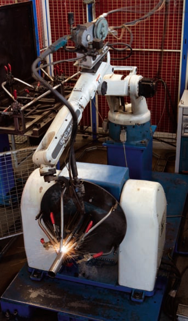 Robot soldant una peça en taula amb dos eixos auxiliars
